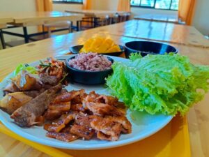 肉料理、野菜、キムチ、紫米、マンゴーが盛られたプレート