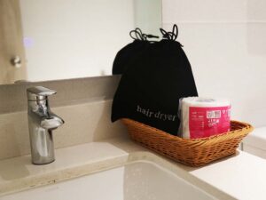 バスルームの洗面台に置かれたドライヤーとトイレットペーパー