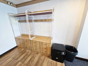 部屋の入り口付近に置かれた2台のワードローブ、冷蔵庫、洗濯物カゴ