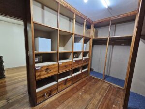 複数の収納棚と引き出しが備わった木製の共用ワードローブ