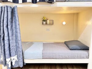カーテン、コンセント、照明が備えられた二段ベッド内の1スペース