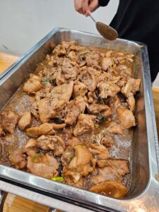昼食時にスタッフが配膳している、フィリピン料理のチキンアドボ