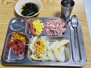 コーンビーフライスとスープ、牛肉炒め、焼売、サラダ、洋梨が並ぶ朝食