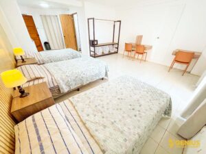 3台のベッドが横一列に並び、ハンガーラックが備わった3人部屋