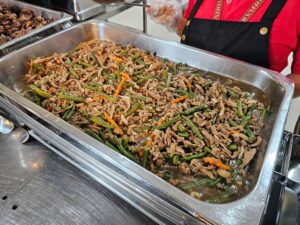 キッチンスタッフが配膳している豚肉と野菜の煮込み