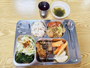 ポークアドボ、チキン、炒飯、サラダ、スープ、パパイヤが盛られた夕食