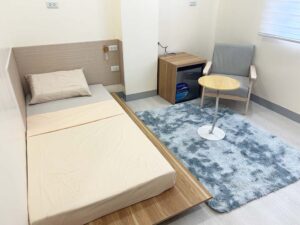 ランプとコンセント付きのローベッドが置かれたシングルルーム