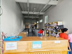 受付カウンター越しに見た洗濯機が並ぶランドリールームとスタッフ