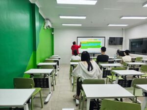 インタラクティブボードを使用してIELTSの授業を行う講師と4人の生徒