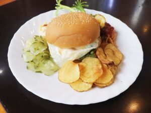 エッグハンバーガー、ピクルス、チップス、パスタが盛られたプレート