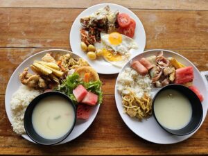 目玉焼き、スープ、野菜、揚げ物、果物などが盛られた朝食
