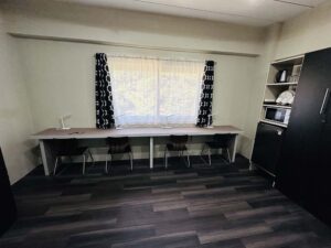 4脚の椅子と4つのスタンドライトが並ぶ、窓際に設置された長い勉強用テーブル