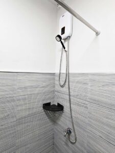温水器付きシャワーと蛇口、小物トレイが付いたシャワーエリア