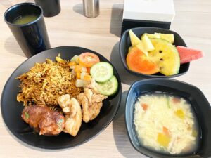 フライドチキン、ビリヤニと野菜に、スープと果物が添えられた食事