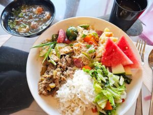 チキン、ビーフの炒め物、パンシット、ゆで野菜、スイカが並んだ昼食