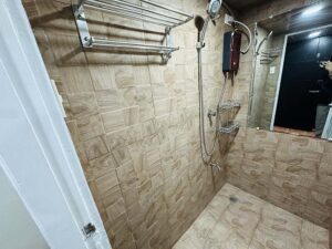 タオルラック、小物置きラック、温水シャワー、大きな鏡が設置された共用シャワールーム