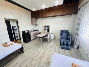 ベッド側から見た、キッチン、テーブル、マッサージチェアが設置された部屋