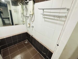 大きな鏡、温水シャワー、タオルハンガーのあるタイル張りのシャワールーム