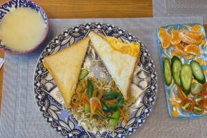 玉子焼きサンドイッチと焼きそば、スープ、野菜、みかんの朝食