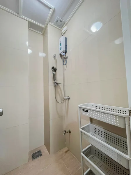 電気式シャワーヒーターとハンドシャワー、蛇口、3段の収納ラックを備えた1人部屋Bのシャワールーム