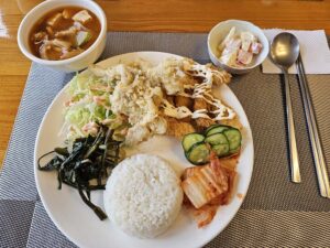 2種類の揚げ物、野菜炒め、フルーツサラダ、ご飯、スープの昼食
