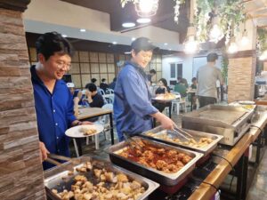 主菜の並ぶカウンターから料理を取っている2人の生徒