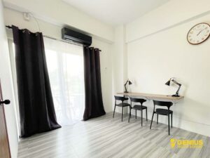 3人用の机、室外機付きエアコンのある室内とシティービューのバルコニー