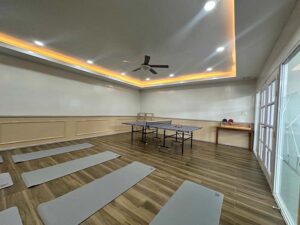 ヨガマットが並び、部屋の後ろに卓球台が置かれたヨガルーム