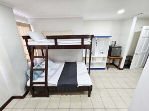 抱き枕付き二段ベッドと収納棚、冷蔵庫のある室内