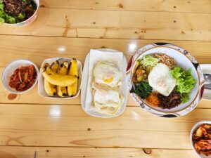 ビビンバ、目玉焼き、バナナ、キムチが並ぶ食卓