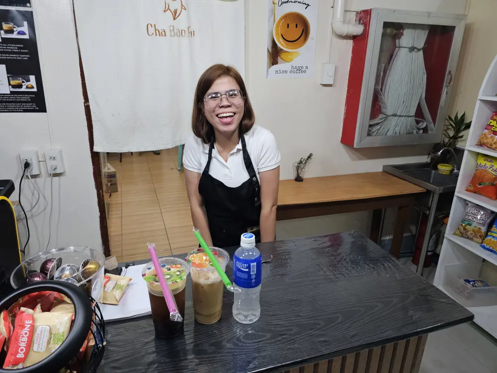 学校カフェカウンターの後ろに立つ明るくフレンドリーなフィリピン人スタッフ