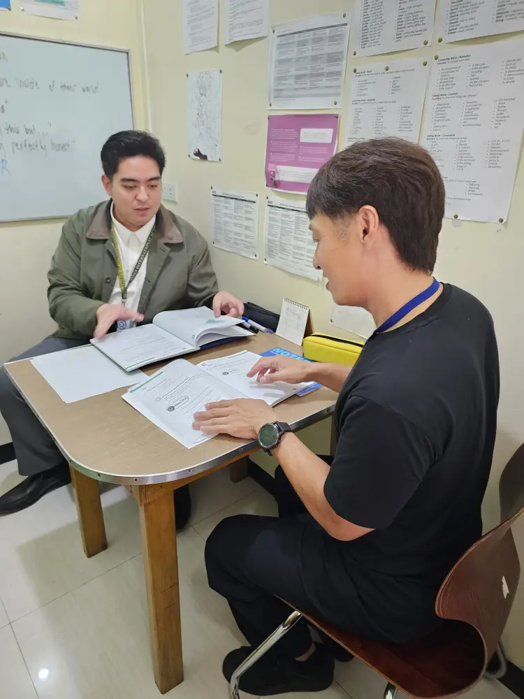 IELTS体験授業中に本をめくる生徒と教師