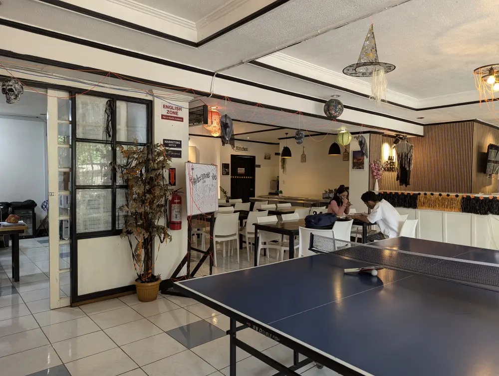 ダイニングエリアに置かれた卓球台と奥のテーブルで授業を行う講師と学生