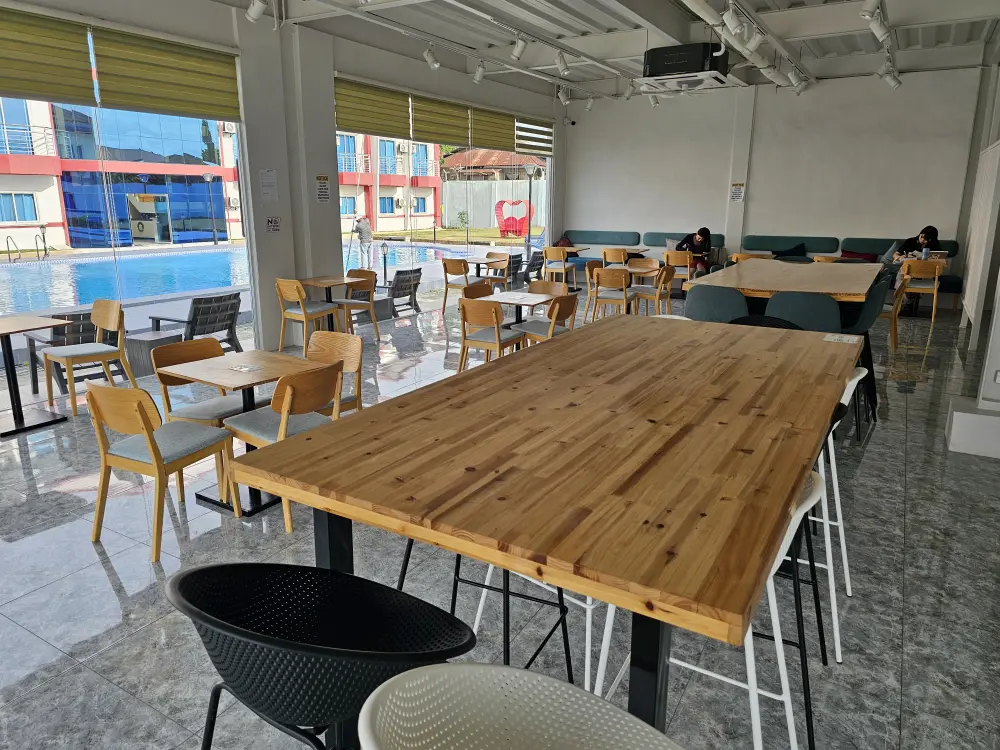 大小のテーブルが並ぶ校内カフェで自習をしている2人の学生