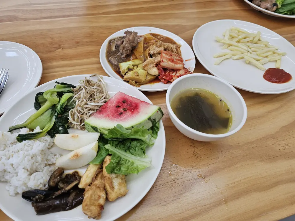 昼食時のテーブルに置かれたフライドポテト、スープ、肉、野菜の料理