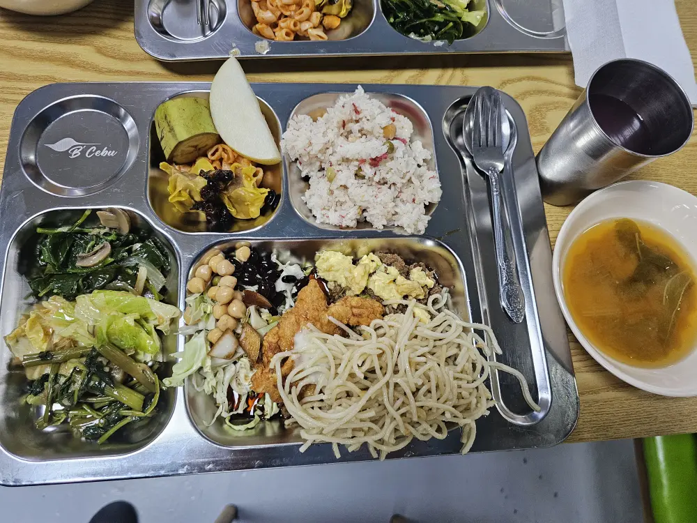 ご飯、フライドチキン、パスタ、サラダ、野菜炒めが並ぶボリューム満点のランチ