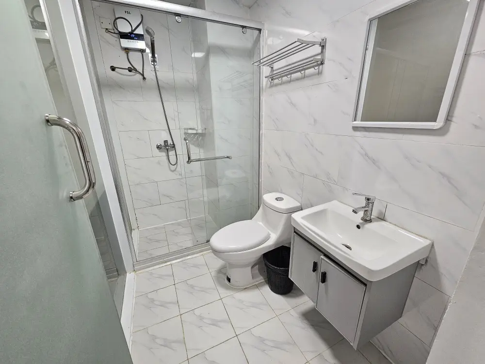 ガラスで仕切られたシャワーエリア、トイレ、洗面台があるタイル張りのバスルーム