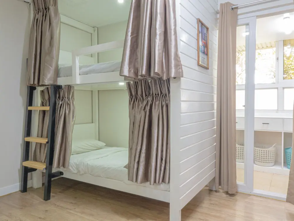 BECI Cityの女性用4人部屋に設置されたカーテンと梯子付き2段ベッド