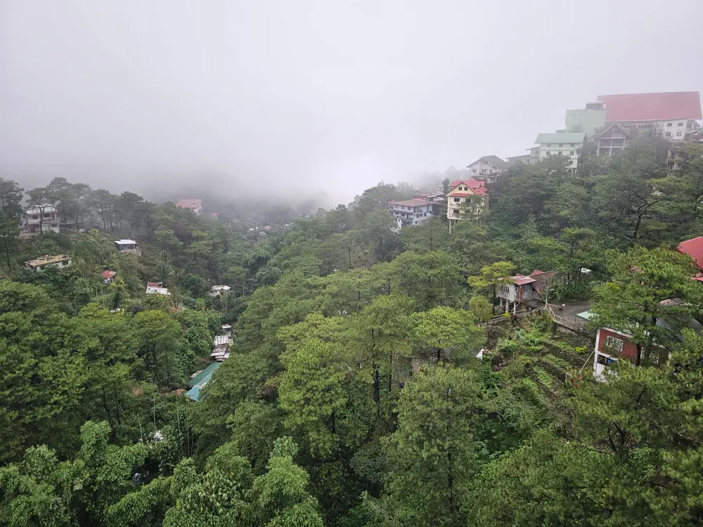 モノルの校舎屋上から見た、霧に包まれた山々と住宅の景色