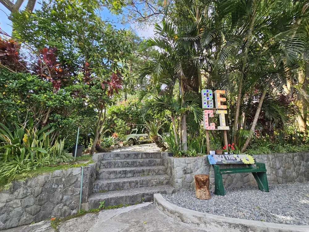 熱帯植物に囲まれたEOPキャンパスの庭とその入口に建っているBECIの看板