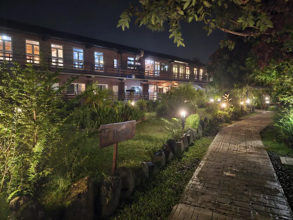 夜にライトアップされた緑豊かなJIC Premiumの校庭と学生寮の外観