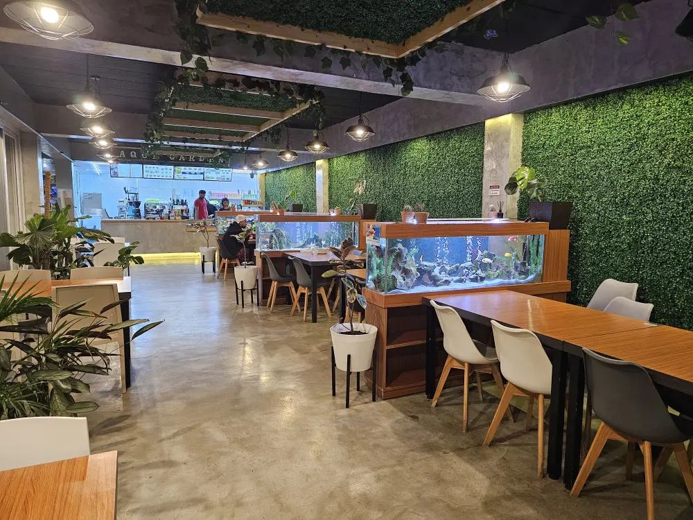 Aqua Garden Restaurantのメインダイニング全景とカウンターに立つ2名のスタッフ