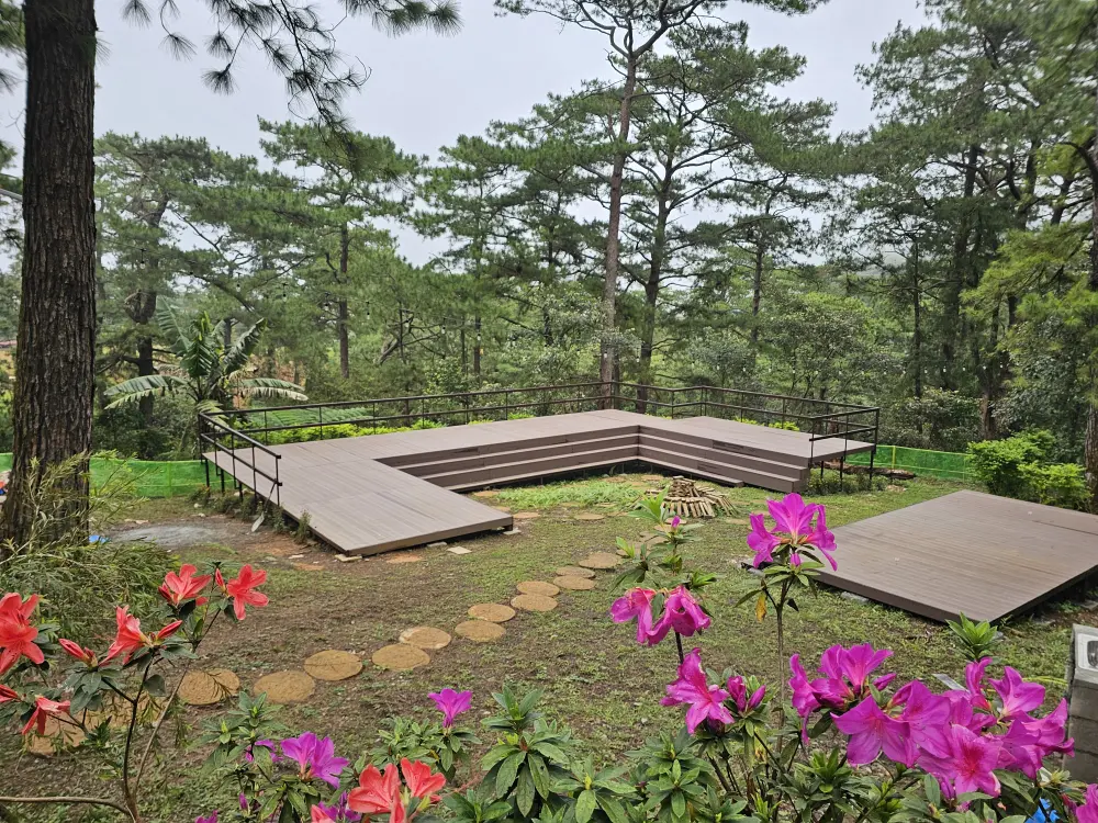 松の木と花に囲まれたキャンプエリアにあるU字型の高床ステージ