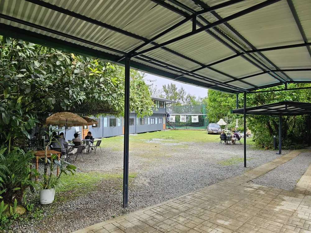 JIC Premiumの校庭にあるパラソル付きテーブルで授業を行う講師と学生