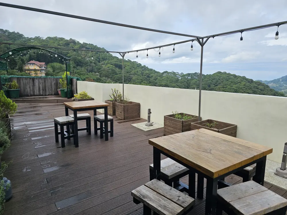 MONOLの校舎屋上のピクニックエリアに配置された2組のテーブルセットと複数の鉢植え