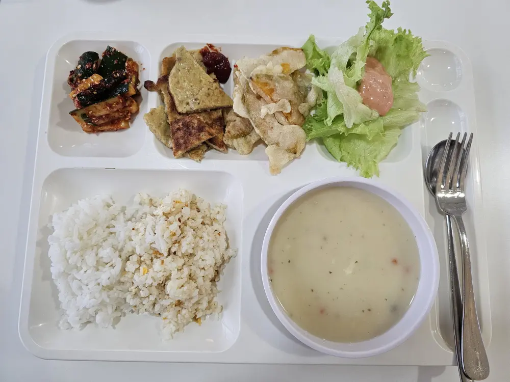 きゅうりキムチ、チヂミ、かぼちゃ天ぷら、サラダ、クラムチャウダーが盛り付けられた朝食