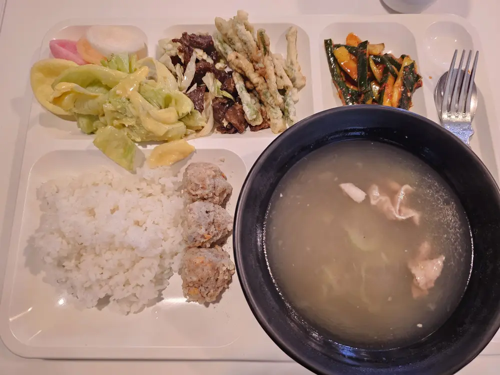 フィリピン料理の牛肉炒めと豚肉団子、シーザーサラダ、チキンヌードルスープが盛り付けられた夕食