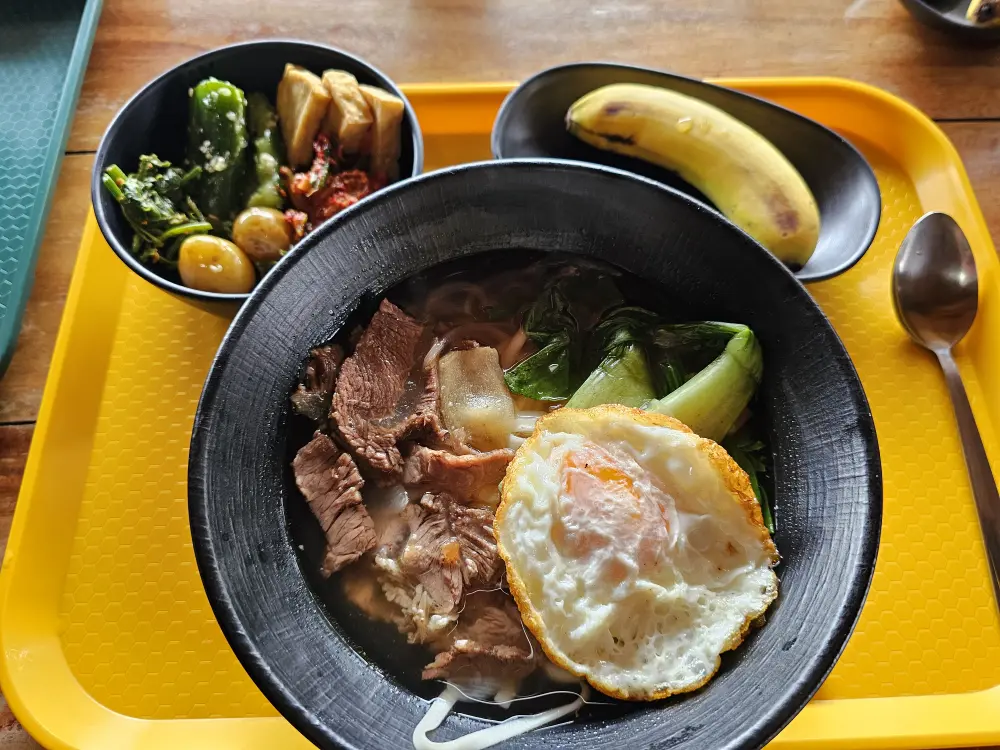半熟目玉焼きとチンゲン菜がのった豚肉麺と韓国風副菜数品、バナナの昼食