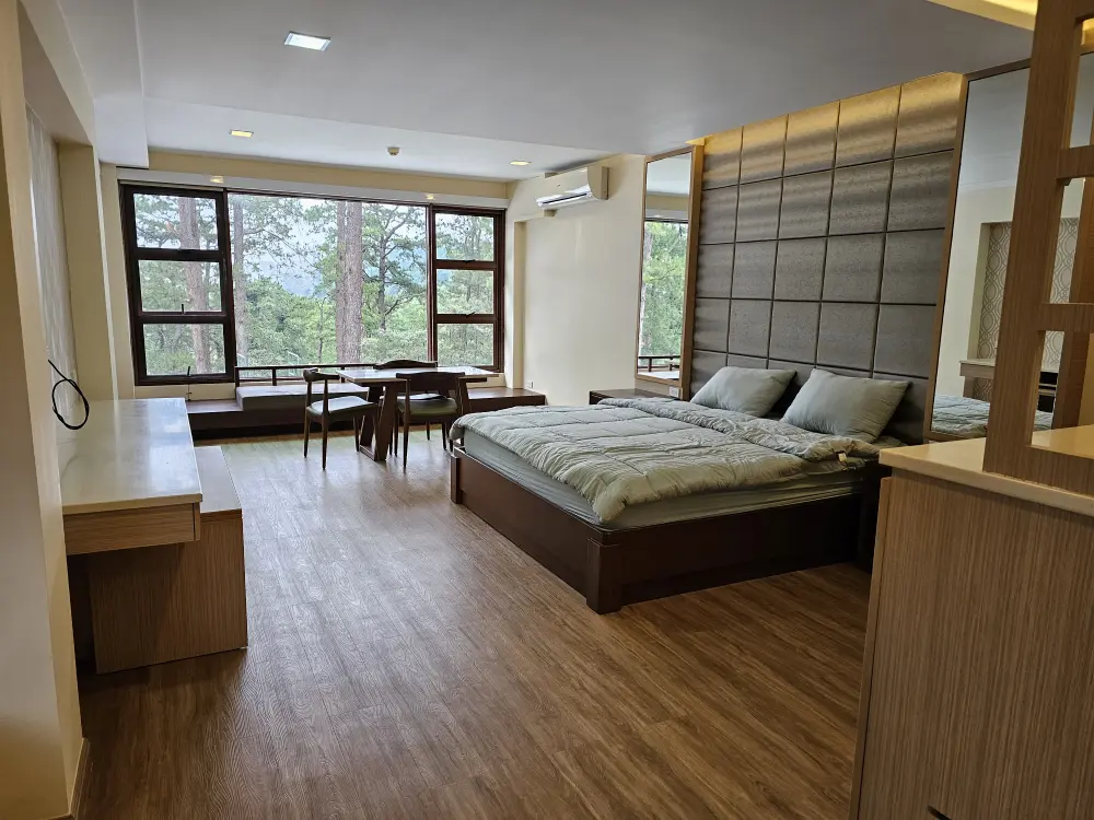 大きな窓、キングサイズベッドとエアコン、テーブルセットを備えたプレミアムスイートルーム