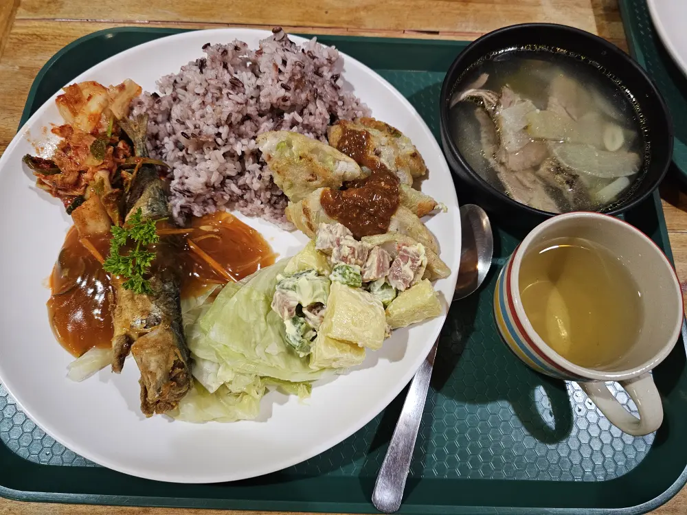 魚の唐揚げ、韓国風紫米とチジミ、ポテトサラダに豚肉のスープが添えられた夕食